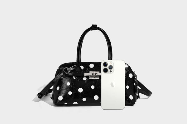 Glossy structured polka-dot satchel bag with dual top handles, silver turn-lock hardware, and detachable shoulder strap