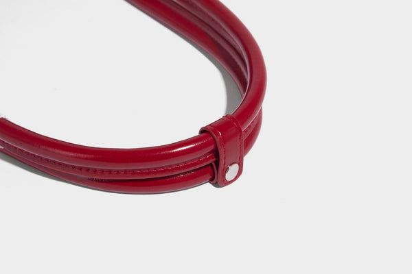 Kleine, formstabile, glänzende Schultertasche mit weißer Paspelierung, Spitzenschleife und Anhänger mit roter Perle, seitlichen Reißverschlusstaschen und silberfarbenem