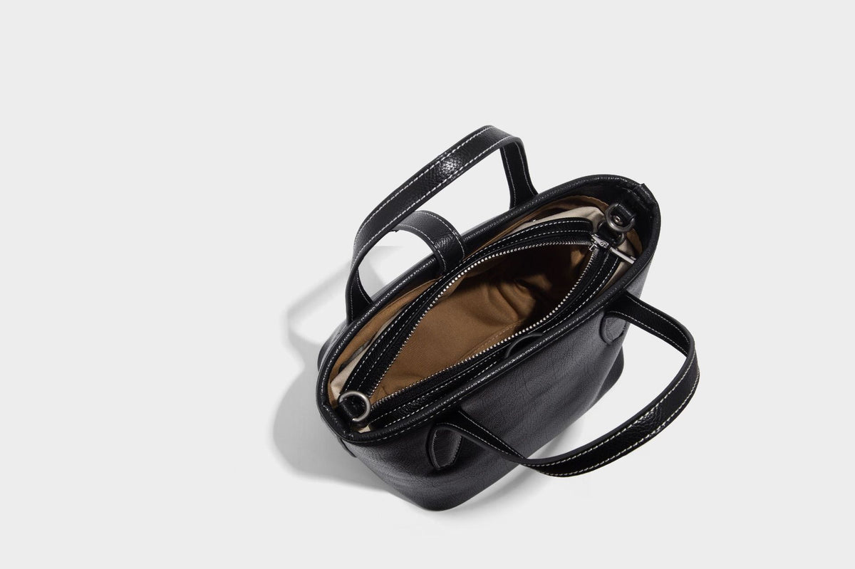 Compact structured bucket tote bag with pebbled textured finish, dual top handles, silver-tone lock hardware, and detachable