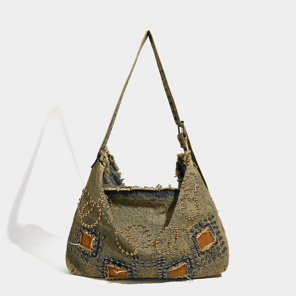 Large distressed denim hobo shoulder bag with mixed-metal rivet detailing and tan leather-look corner trim, front view