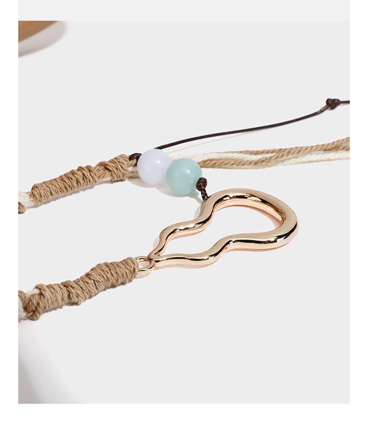 Pebbled leather-look bucket tote bag with rolled double handles, drawstring closure, braided cord charm, and detachable