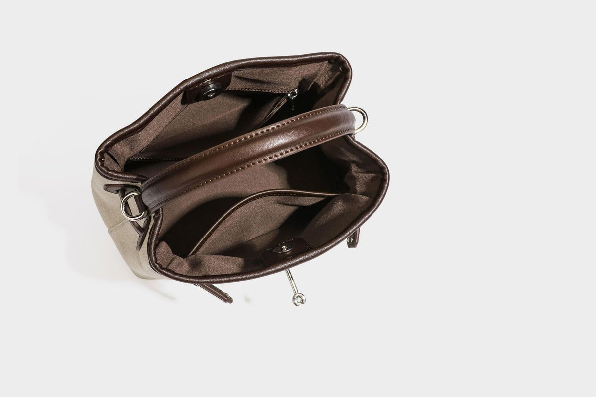 Small structured beige canvas top-handle bag with dark brown leather-look trim, silver turn-lock hardware, and detachable