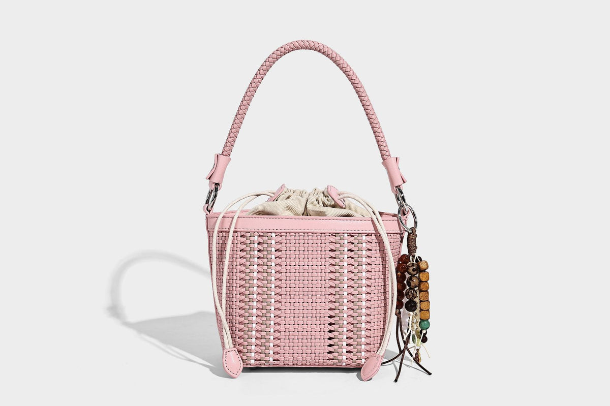 Small woven bucket bag with drawstring top, braided handle, detachable crossbody strap, and silver-tone ring hardware, detail