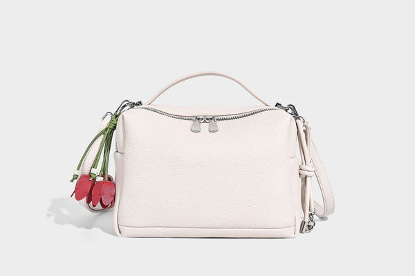 Kleine strukturierte Crossbody-Tasche mit Tragegriff aus genarbtem Material, Reißverschluss, silberfarbenen Beschlägen und optionalem Quastenanhänger