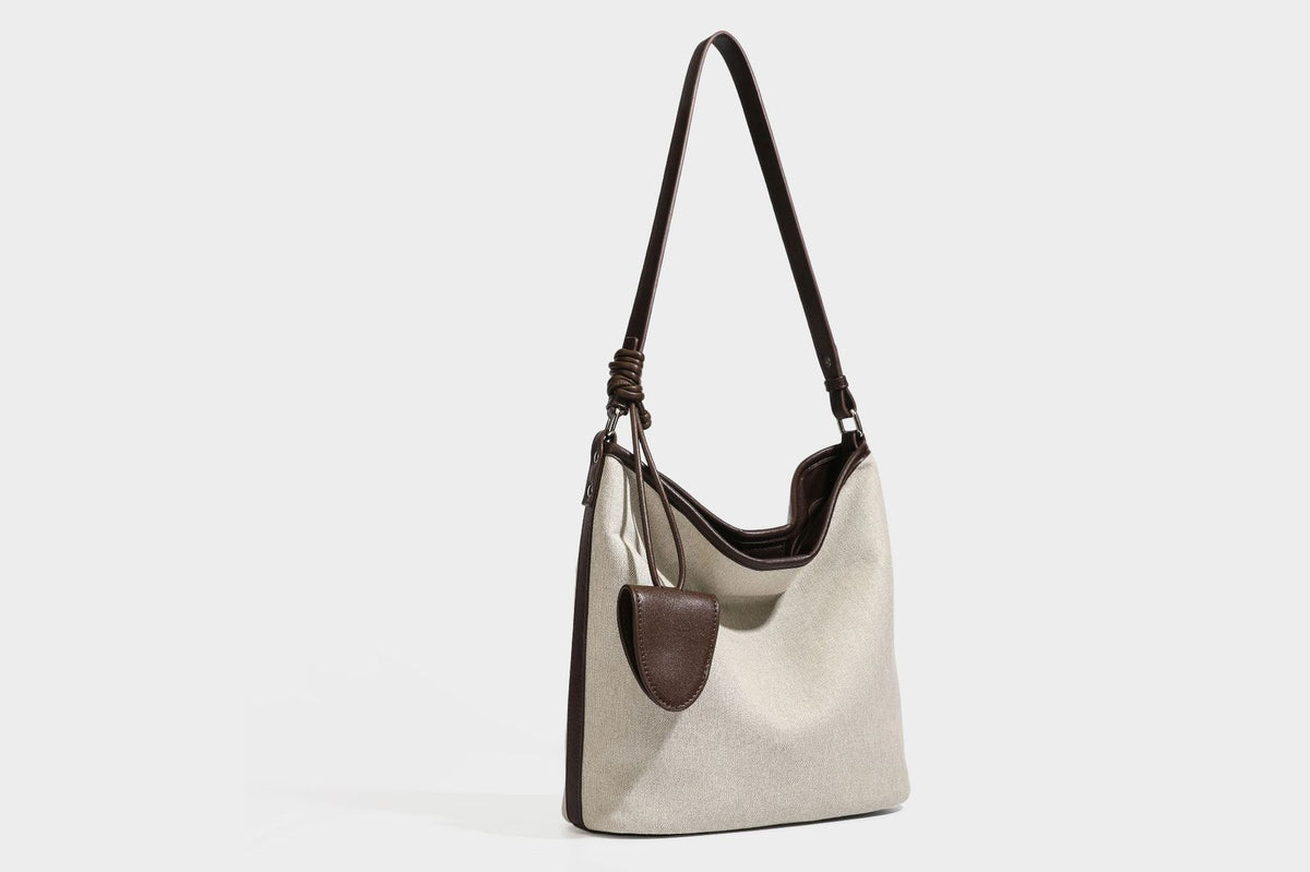 Oatfarbene Canvas-Schultertasche mit dunkelbraunem Besatz in Lederoptik, langem verstellbarem Riemen und angebrachter Mini-Tasche mit Überschlag, Detailansicht