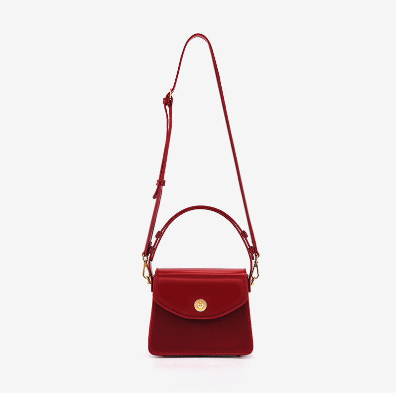 Kleine strukturierte Henkeltasche mit Überschlag in tiefem Rot, glatter Lederoptik, goldfarbenem Drehverschluss, kurzem Henkel und