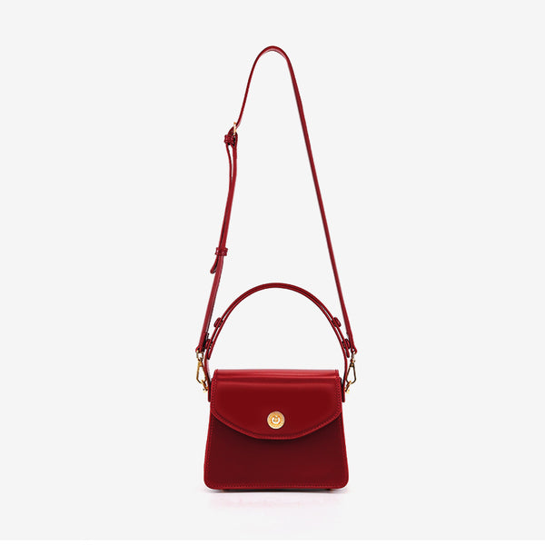 Kleine strukturierte Henkeltasche mit Überschlag in tiefem Rot, glatter Lederoptik, goldfarbenem Drehverschluss, kurzem Henkel und