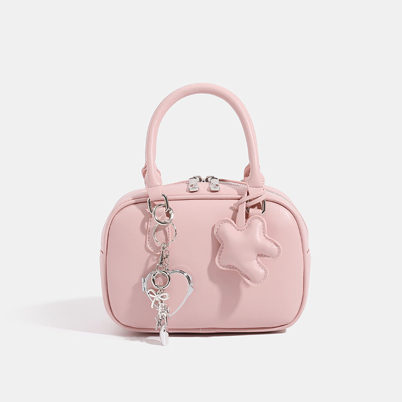 Small structured rounded-rectangle mini handbag with glossy leather-look finish, top zip closure, silver-tone hardware, and