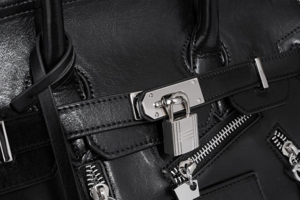 Structured black leather-look satchel bag with silver padlock hardware, front zip pockets, key charms, and top handles