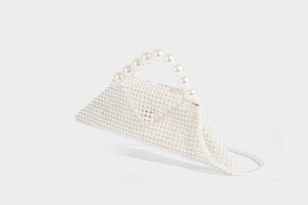 Small structured triangle clutch bag covered in glossy pearl beads with an arched pearl top handle and silver snap closure