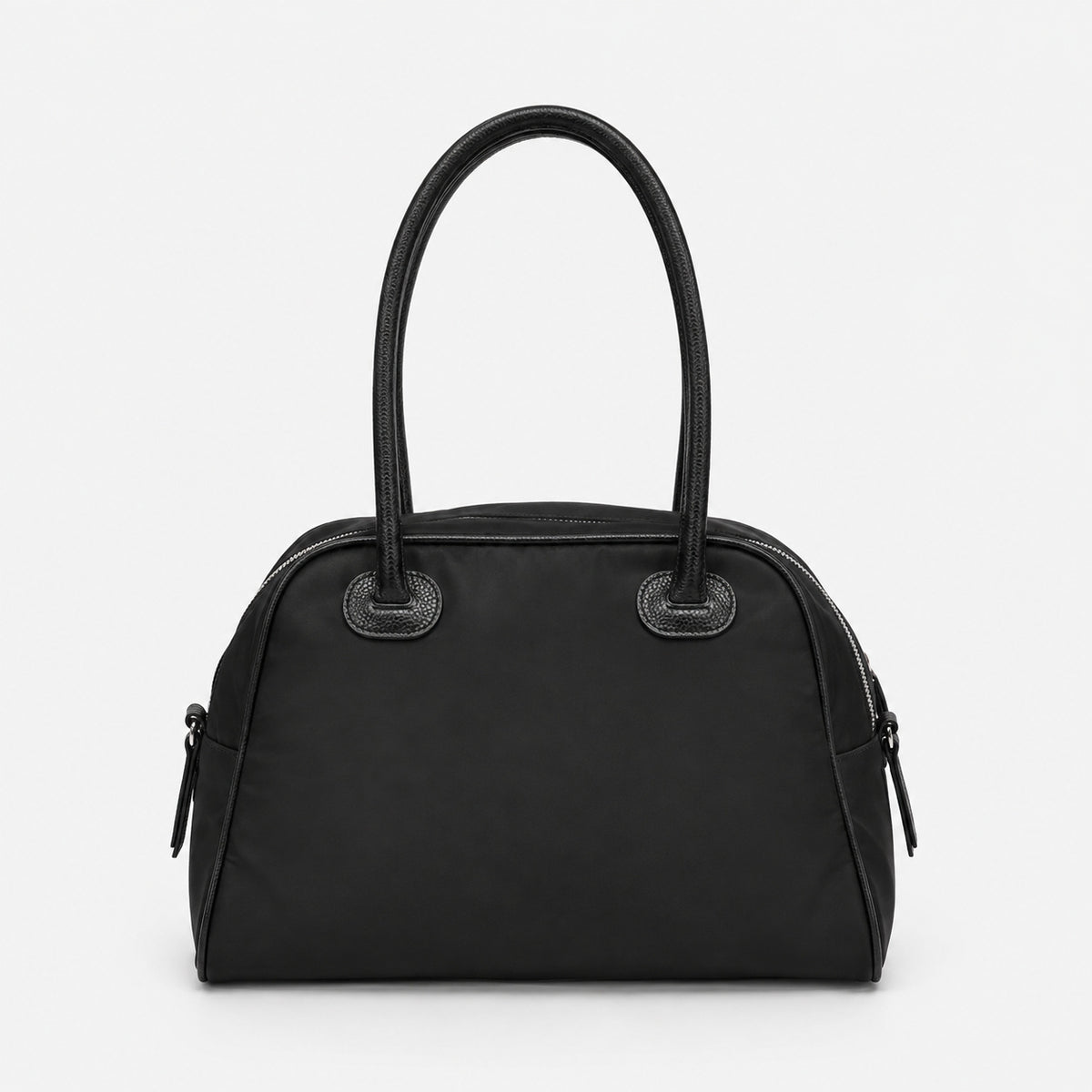 Structured dome top-handle bag in matte nylon with pebbled vegan leather-look trim, zip-top closure, front slip pocket, and