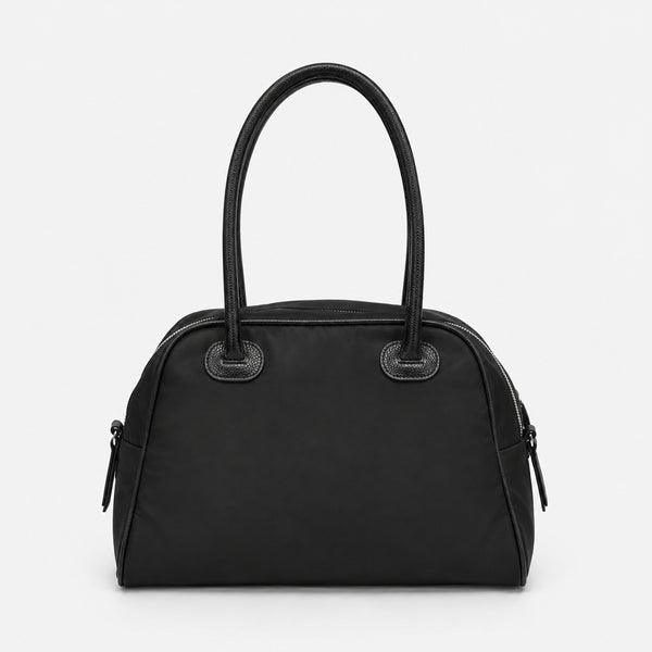 Structured dome top-handle bag in matte nylon with pebbled vegan leather-look trim, zip-top closure, front slip pocket, and