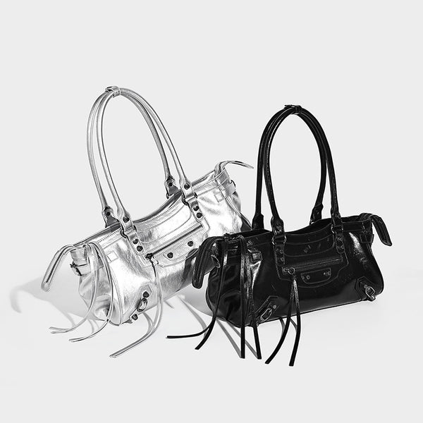 Längliche Schultertasche in Zylinderform mit glänzender Lederoptik, silberfarbenen Nieten, seitlichen Quasten und mehreren Außenreißverschlüssen