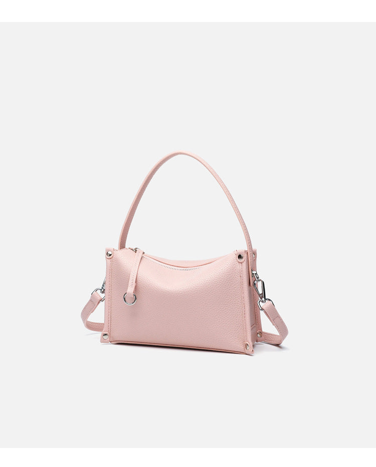 Small structured pebbled-finish convertible bag with silver corner studs, zip top, and detachable shoulder strap, detail view