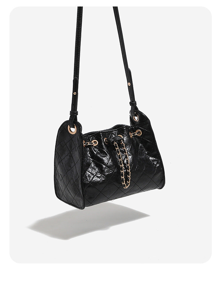 Glossy diamond-quilted drawstring bucket bag with gold-tone chain strap and eyelet hardware, detail view 10