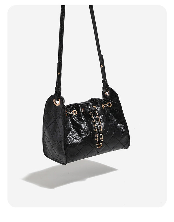 Glossy diamond-quilted drawstring bucket bag with gold-tone chain strap and eyelet hardware, detail view 10