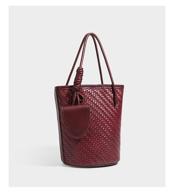Structured woven-texture leather-look bucket bag in brown with knotted top handles, small front flap pouch, and adjustable