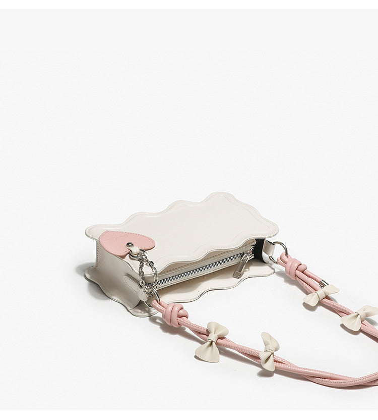 Small structured scalloped-edge shoulder bag with bow-tied pink cord strap and silver heart charm pendant, detail view 10