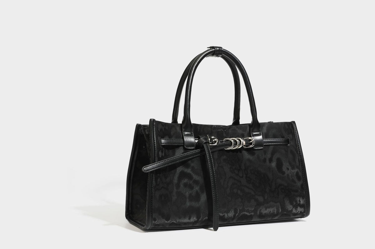 Structured leopard-print tote bag with glossy satin-like finish, dual rounded top handles, silver buckle-and-ring front
