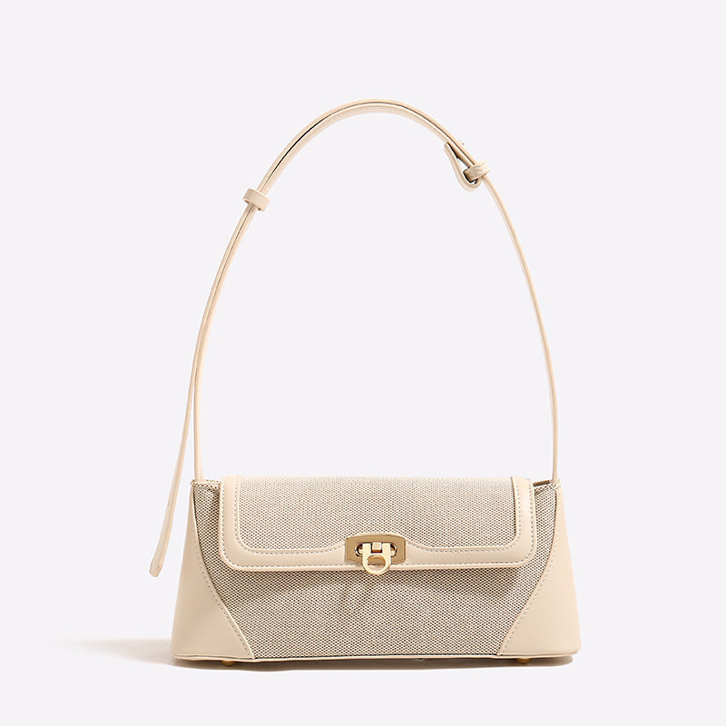 Structured trapezoid flap shoulder bag with canvas-textured body, smooth contrast trim, and gold-tone turn-lock clasp, detail