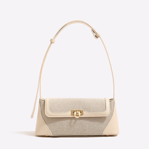 Structured trapezoid flap shoulder bag with canvas-textured body, smooth contrast trim, and gold-tone turn-lock clasp, detail