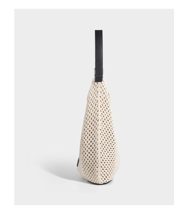 Cream openwork crochet hobo bag with black leather-look strap and trim patch accent, slouchy teardrop silhouette, detail view
