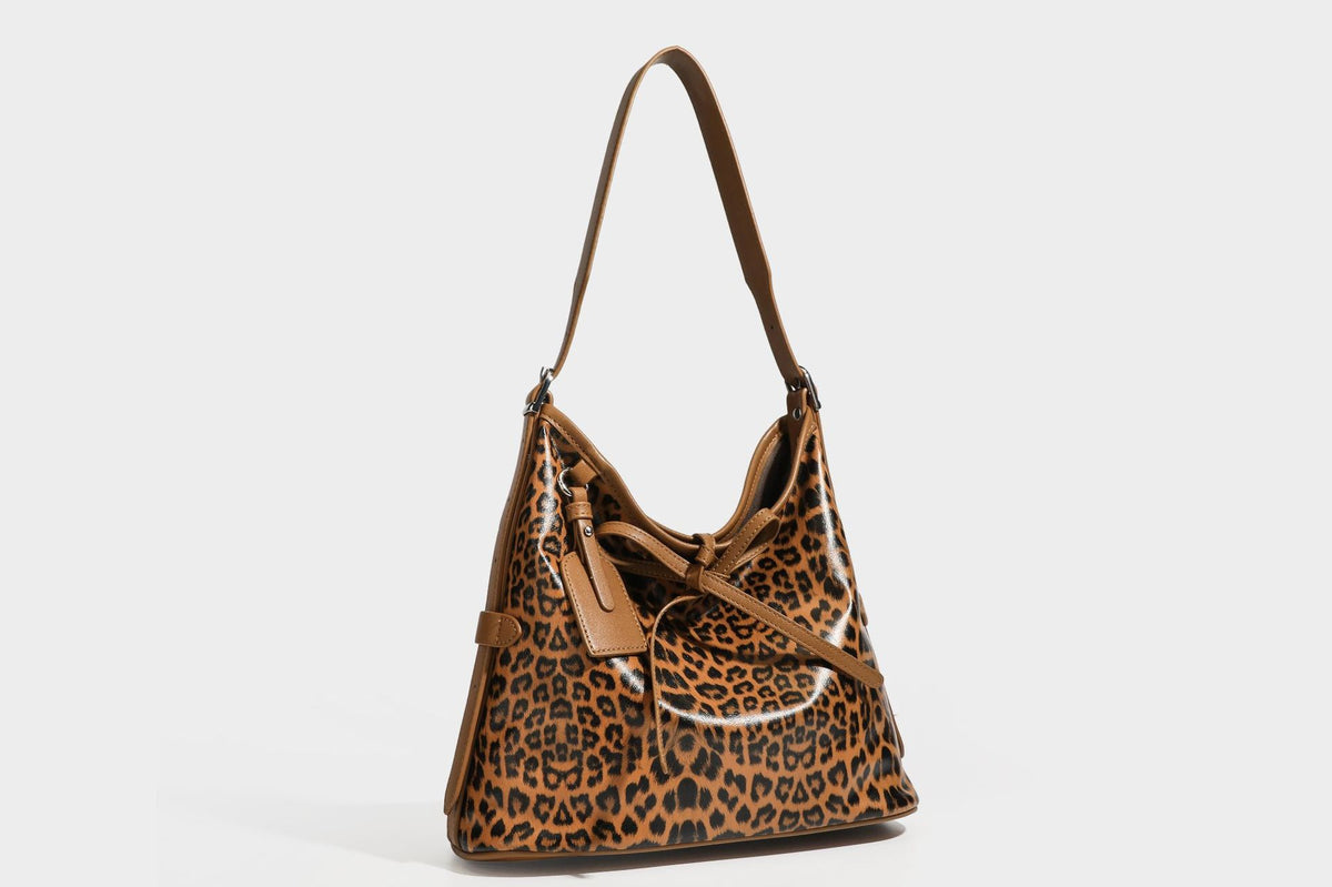 Slouchy leopard print shoulder hobo bag with black leather-look trim, tie-top closure, and single long strap, detail view 26