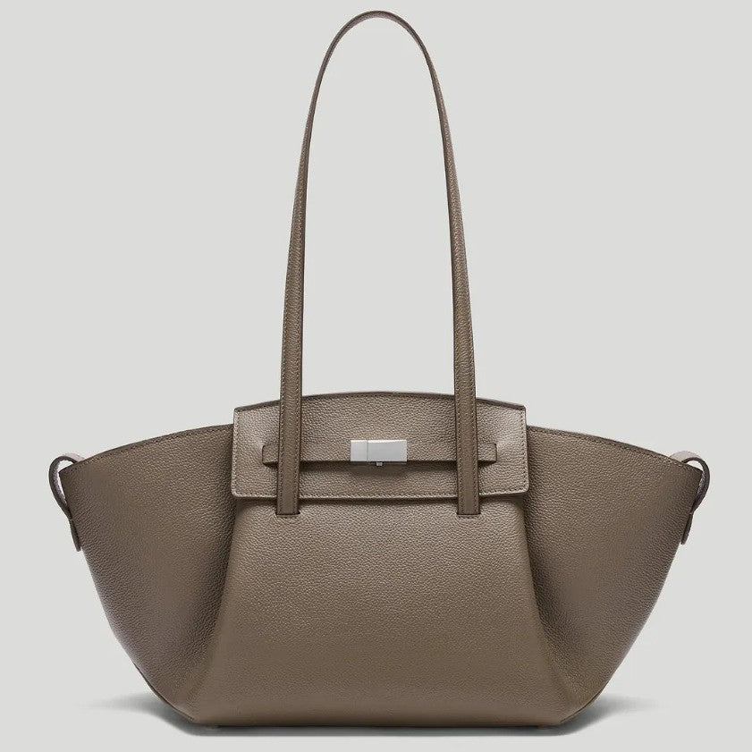 Black pebbled trapezoid tote bag with gold turn-lock hardware and double top handles, detail view 2
