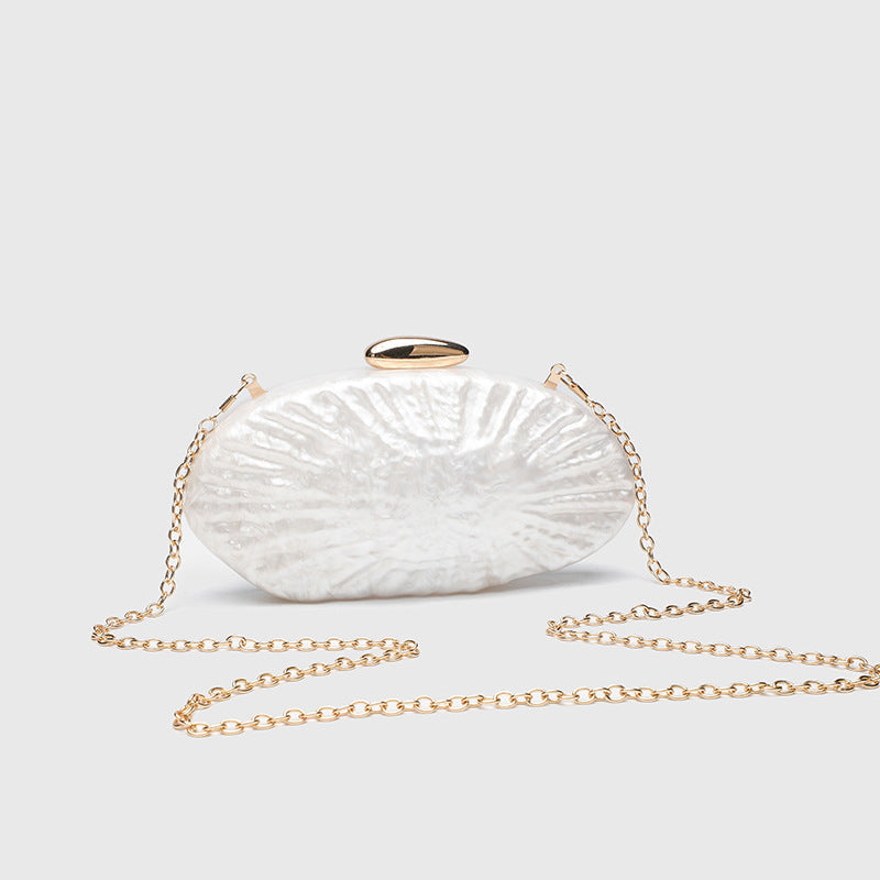 Oval pearl-finish shell clutch bag with gold-tone clasp and removable gold link chain strap, detail view 2