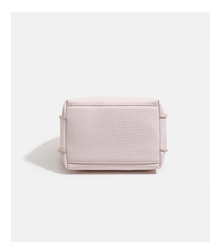 Compact pebbled leather-look shoulder bag with crossed silver-toned metal front closure, short top handle, and long, detail