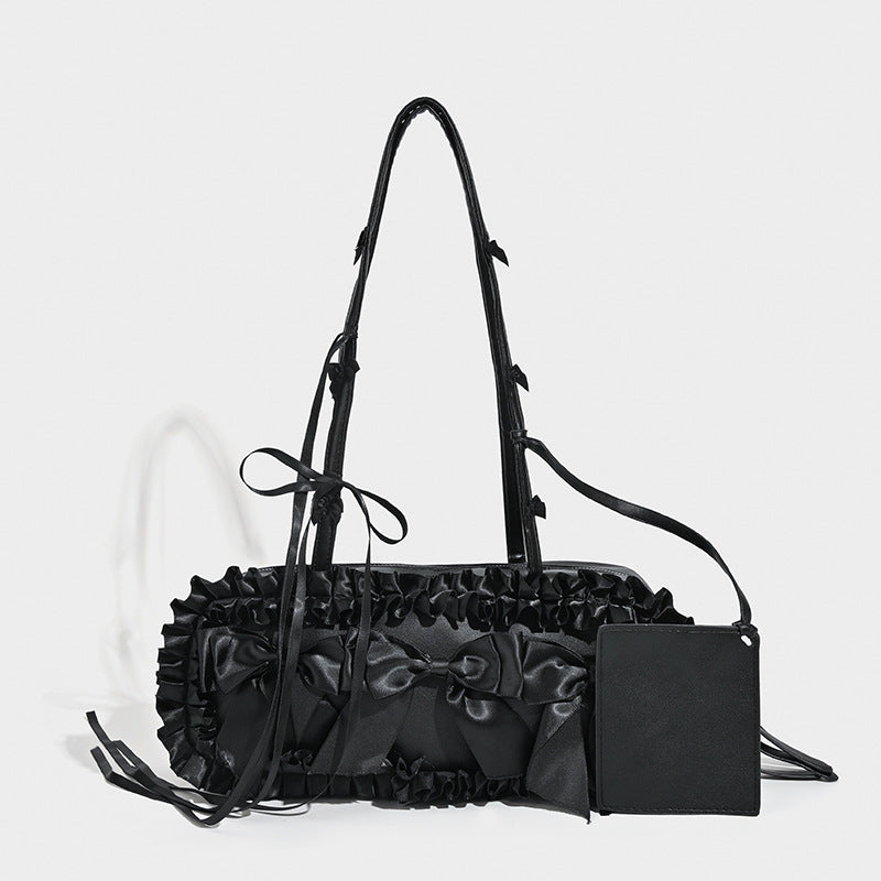 Black leather-look structured tote bag with gathered ruffle trim, ribbon bow accents, top zip closure, and attached card