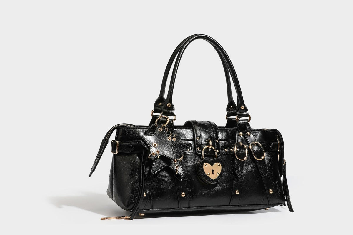 Glossy dark brown structured Boston satchel with heart-shaped lock charm, star pendant, rivet studs, multi-strap front panel